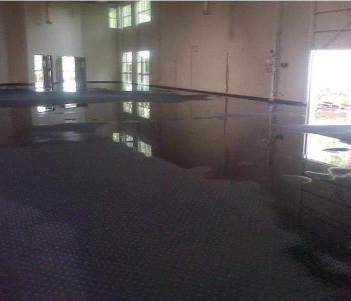 pooling water on carpet of large commercial building with open bays and doors